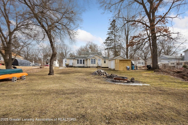 view of yard with a shed, a fire pit, and an outbuilding