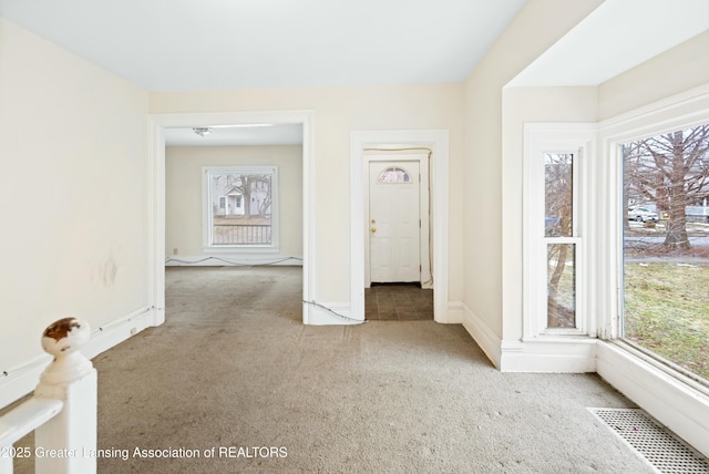 empty room with carpet, visible vents, and baseboards