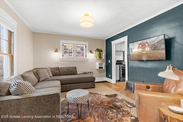 living room with light wood-style flooring, ornamental molding, and baseboards