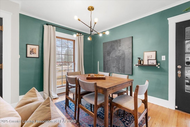 dining space featuring a chandelier, ornamental molding, baseboards, and wood finished floors