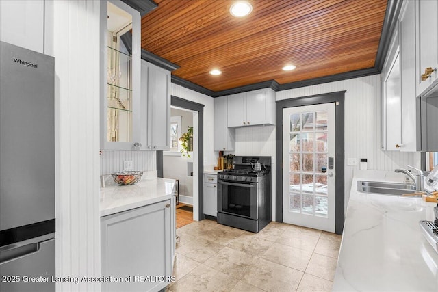 kitchen with wooden ceiling, a sink, a wealth of natural light, freestanding refrigerator, and range with gas cooktop