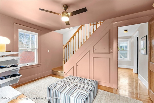 stairway featuring a ceiling fan, baseboards, and wood finished floors