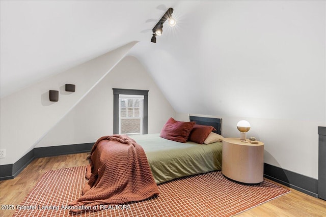 bedroom with vaulted ceiling, ceiling fan, wood finished floors, and baseboards