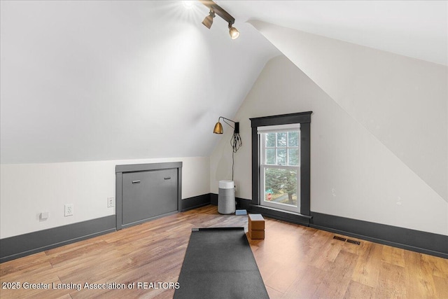 bonus room featuring visible vents, vaulted ceiling, baseboards, and wood finished floors