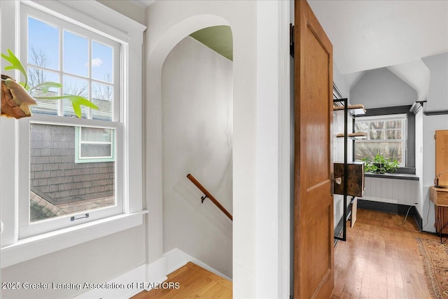 stairway with arched walkways, plenty of natural light, and wood finished floors