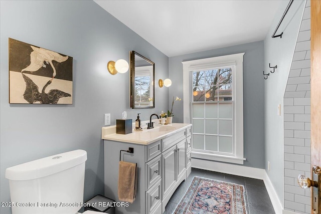 bathroom with baseboards, vanity, toilet, and tile patterned floors