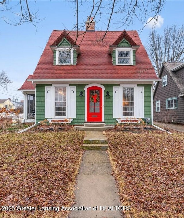 cape cod home with a shingled roof and a chimney