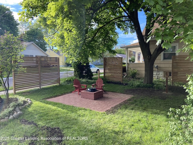 view of yard with a patio area, fence, and a fire pit