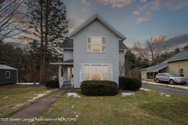 traditional home featuring a shingled roof and a front lawn