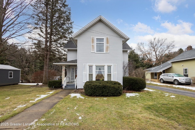 traditional-style house featuring a shingled roof and a front yard