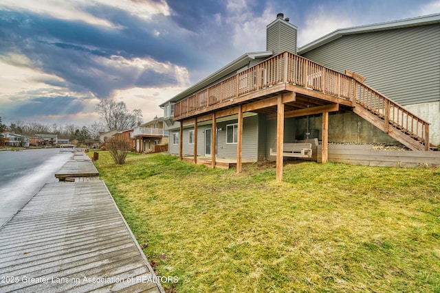 back of property with stairs, a chimney, and a yard