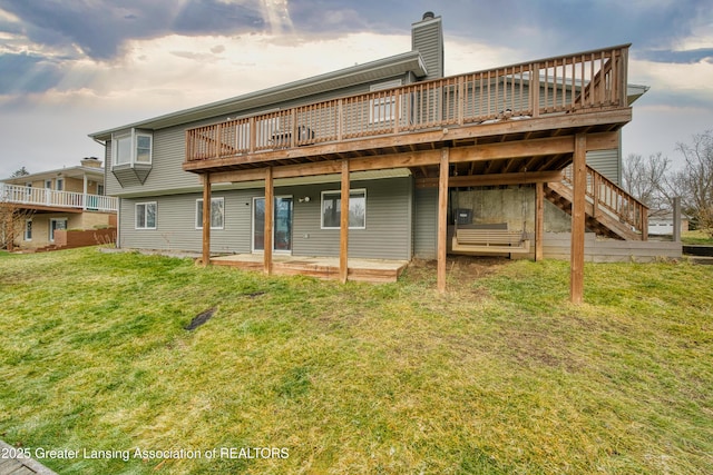 rear view of property featuring a yard, a patio, a chimney, and a wooden deck