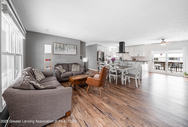 living room featuring ceiling fan, a textured ceiling, and wood finished floors