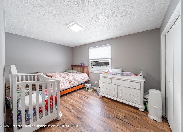 bedroom with a textured ceiling, baseboards, and wood finished floors