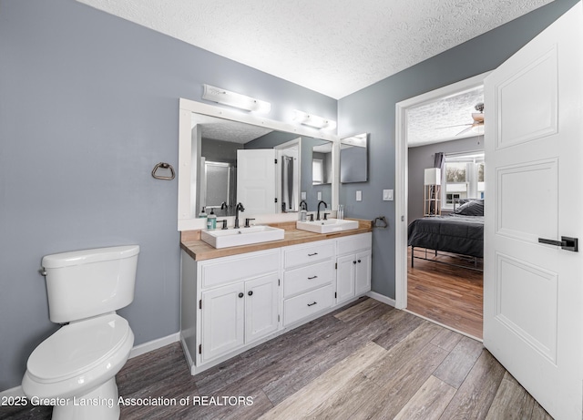 full bathroom featuring a textured ceiling, double vanity, wood finished floors, and a sink