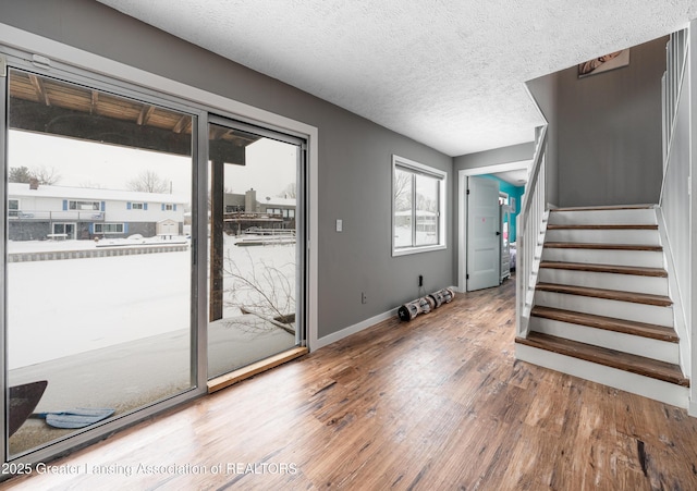 interior space with baseboards, stairway, a textured ceiling, and wood finished floors