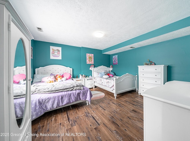 bedroom featuring visible vents, a textured ceiling, and wood finished floors