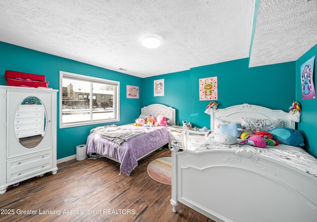 bedroom with visible vents, a textured ceiling, baseboards, and wood finished floors