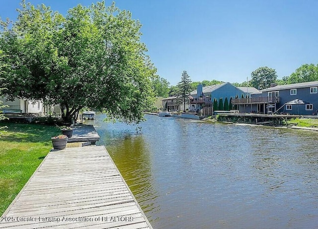 view of dock featuring a water view and a yard