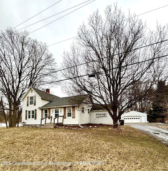 view of front of home with a chimney, an outdoor structure, and a detached garage