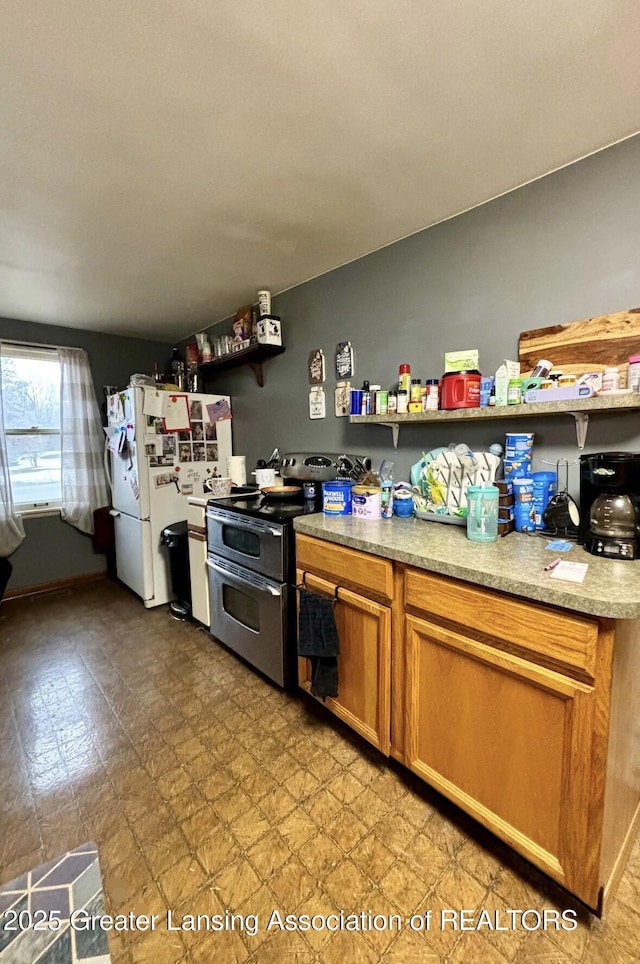 kitchen with brown cabinets, light floors, light countertops, freestanding refrigerator, and double oven range