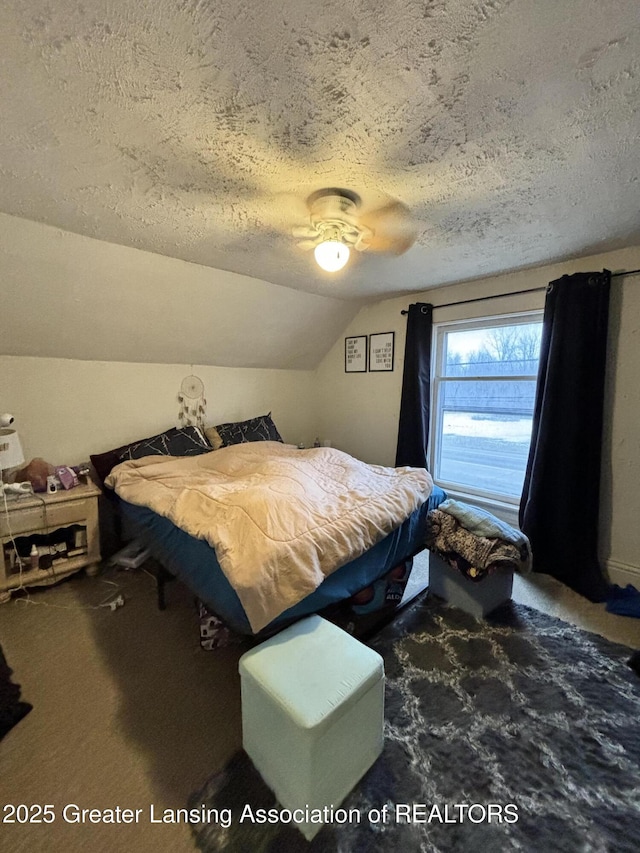 carpeted bedroom featuring ceiling fan, vaulted ceiling, and a textured ceiling