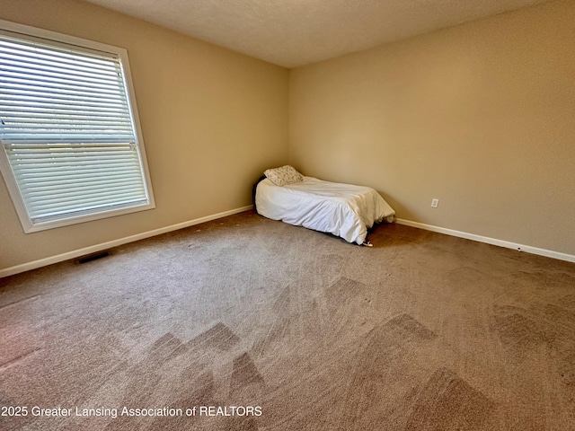 unfurnished bedroom with carpet floors, visible vents, and baseboards