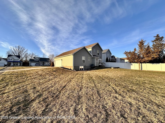 view of side of property featuring a garage, a yard, and fence