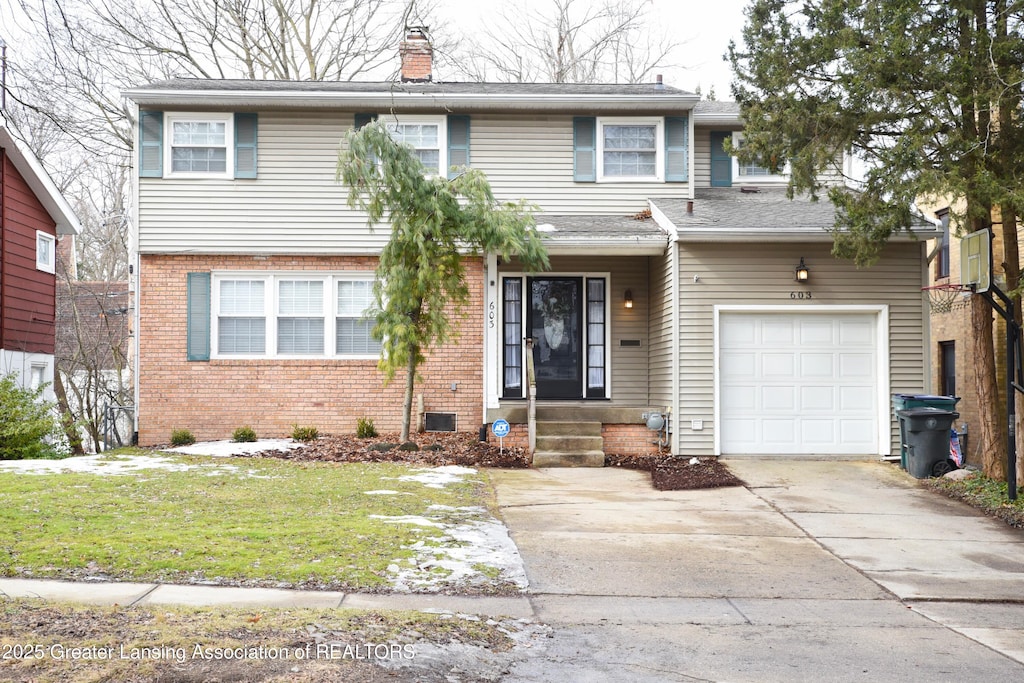 view of front of home featuring brick siding, a chimney, a front yard, a garage, and driveway