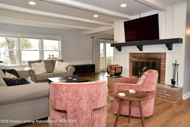 living room featuring light wood finished floors, a brick fireplace, beamed ceiling, and recessed lighting