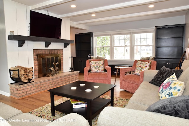 living area with a brick fireplace, wood finished floors, and beam ceiling