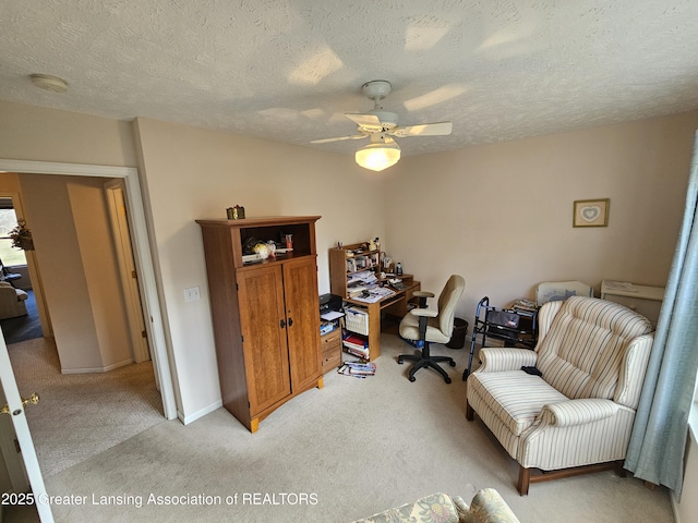 home office featuring light carpet, ceiling fan, baseboards, and a textured ceiling