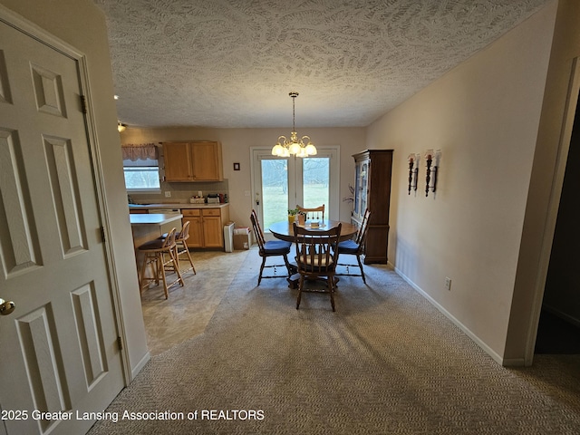 dining area featuring baseboards, a textured ceiling, a chandelier, and a wealth of natural light