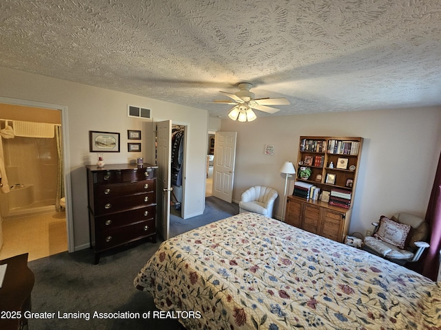 bedroom featuring visible vents, a spacious closet, dark colored carpet, a textured ceiling, and a closet