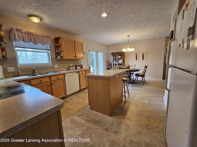 kitchen with white appliances, tasteful backsplash, a center island, open shelves, and a sink