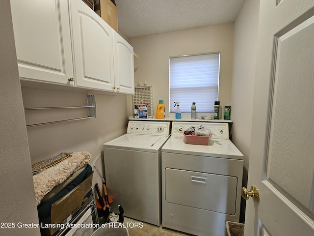 clothes washing area with cabinet space, washer and clothes dryer, and a textured ceiling