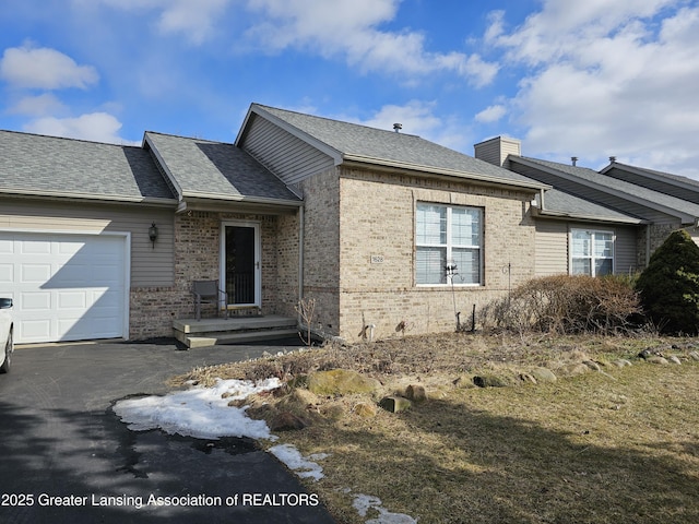 view of side of home featuring a garage, brick siding, and roof with shingles