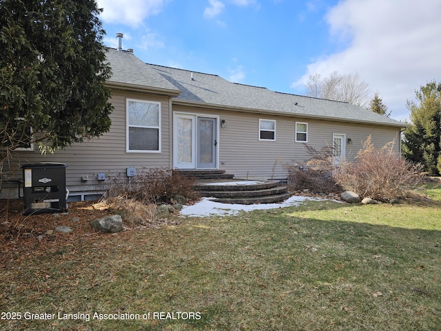 back of property with entry steps, a yard, and roof with shingles