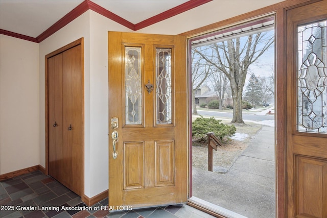 entryway with ornamental molding, stone tile flooring, and baseboards