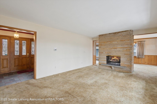 unfurnished living room featuring carpet floors and a stone fireplace