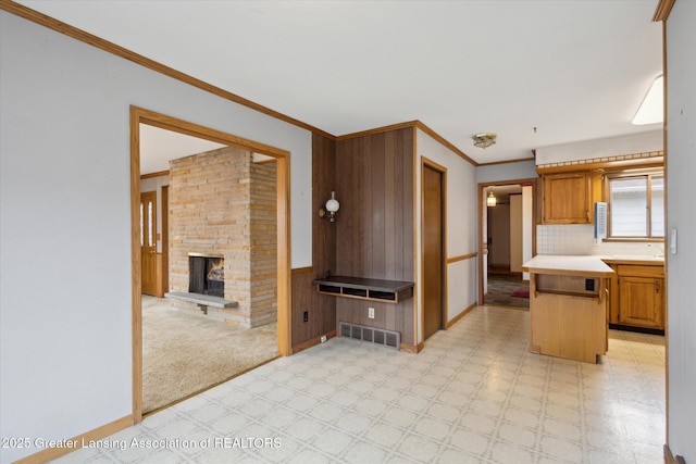 kitchen with light floors, light countertops, visible vents, wainscoting, and a stone fireplace