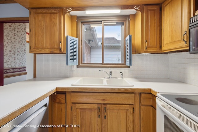 kitchen featuring dishwasher, backsplash, light countertops, and a sink