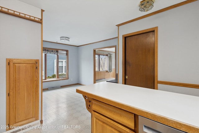 interior space with visible vents, baseboards, light countertops, light floors, and crown molding