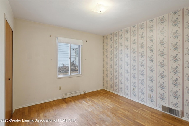 unfurnished room featuring wallpapered walls, visible vents, baseboards, a baseboard radiator, and light wood-style flooring