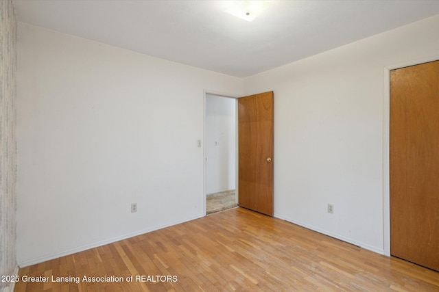 spare room featuring baseboards and light wood-style floors