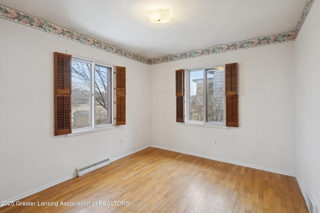 unfurnished room with a baseboard radiator, visible vents, baseboards, and hardwood / wood-style flooring