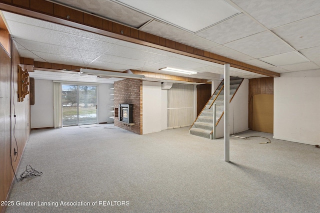 basement featuring carpet floors, a paneled ceiling, a fireplace, and stairs