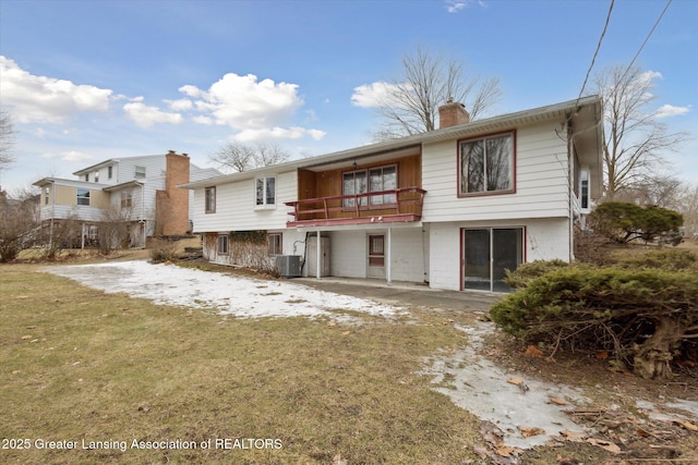 back of house with a patio, a balcony, central AC, a lawn, and a chimney