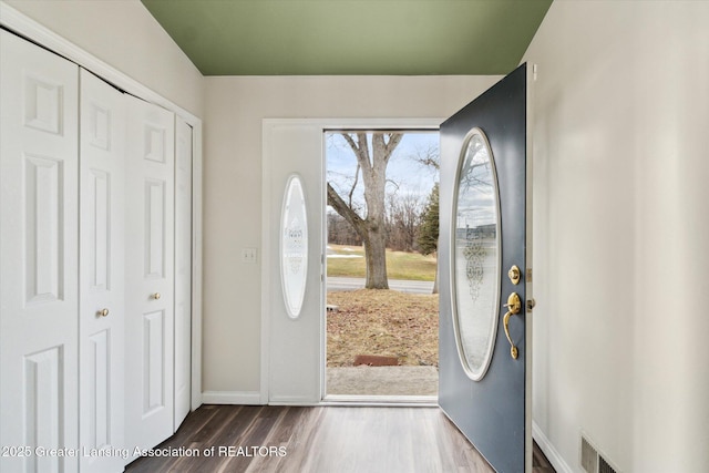 foyer entrance featuring dark wood-type flooring, visible vents, and baseboards