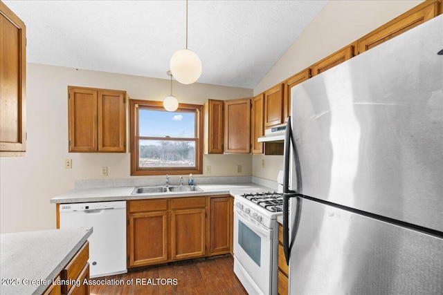 kitchen featuring white appliances, decorative light fixtures, light countertops, under cabinet range hood, and a sink